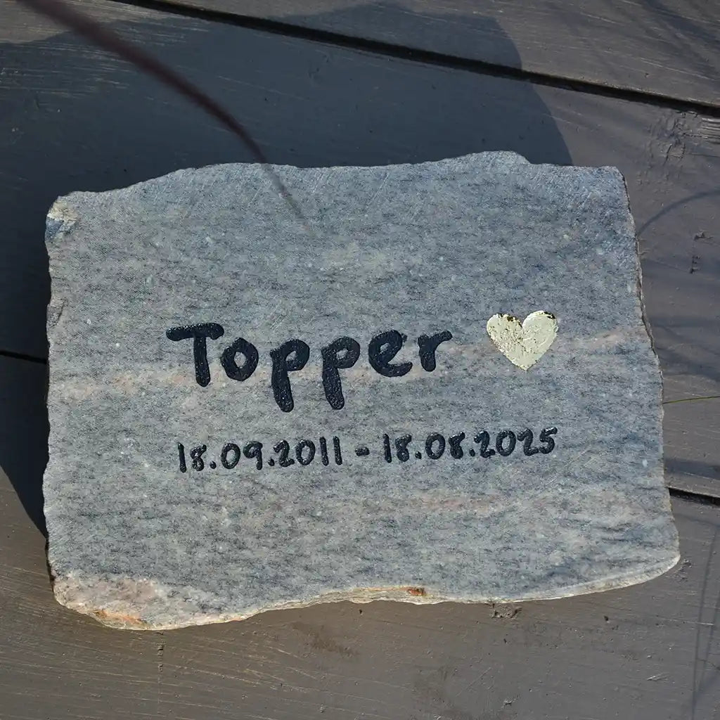 Tiergrabstein mit Namen, Lebensdaten und goldenem Herz mit personalisierter Gravur auf grauem Granitstein