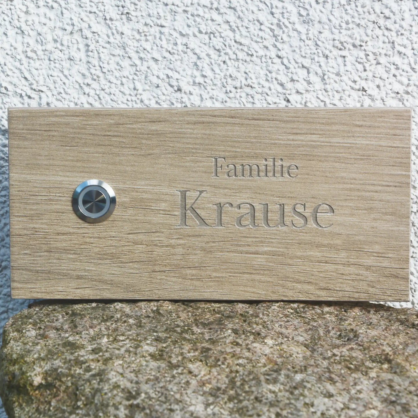 Personalisiertes Klingelschild (20x15 cm) aus beigefarbenen Keramik-Feinsteinzeug im Längsformat mit LED- Edelstahl-Klingeltaster links. Name in Serifenschrift und Groß- und Kleinschreibung 2-zeilig.