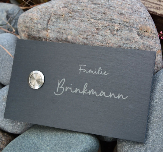 Klingelschild aus Schiefer mit geschnittenen Kanten in 17x10cm Längsformat Edelstahltaster unbeleuchtet linksseitig. Familienname mit Handschrift zweizeilig