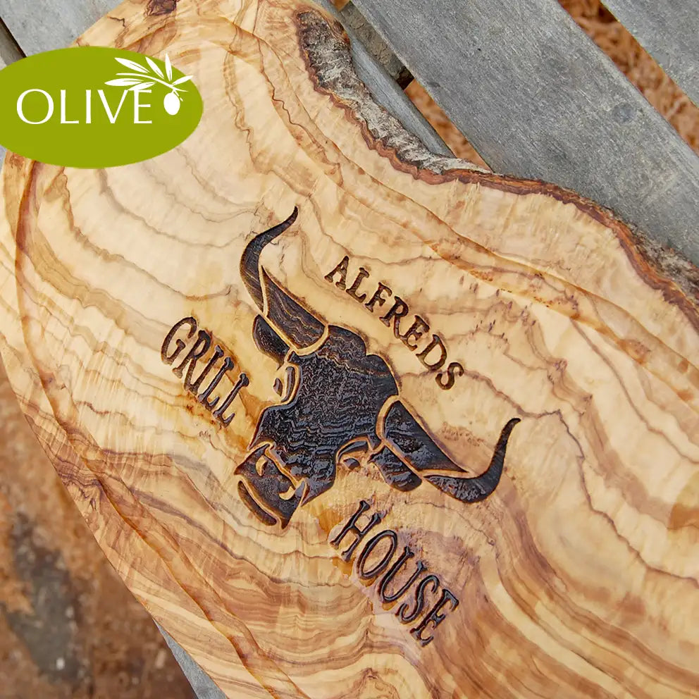 Motiv GRILL HOUSE mit Wunschnamen und stilisiertem Rinderkopf von vorne - Mediterranes Schneidebrett aus Olivenholz mit Saftrille und personalisierten Gravurmotiv - Jeske Design