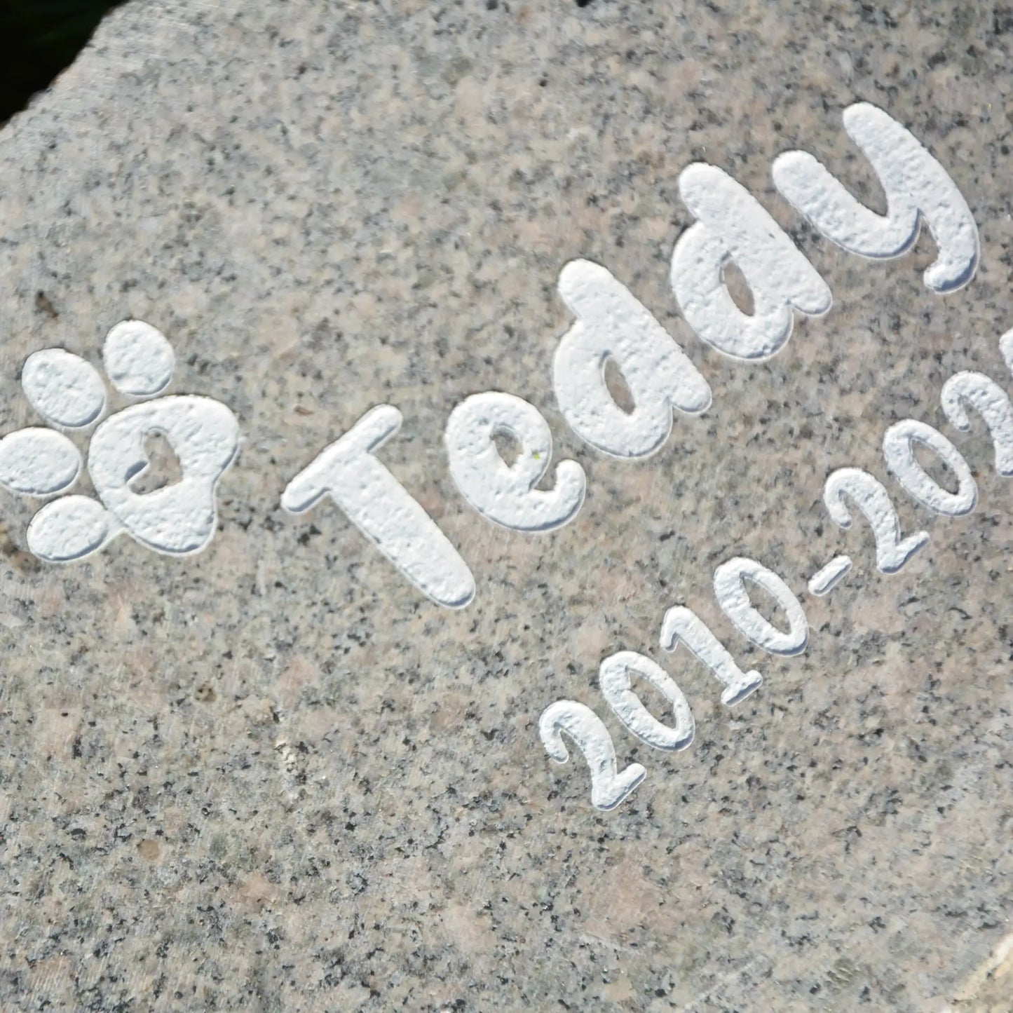 Tiergrabstein Granit mit Pfote und Name. Lebensdaten als weiße Gravur
