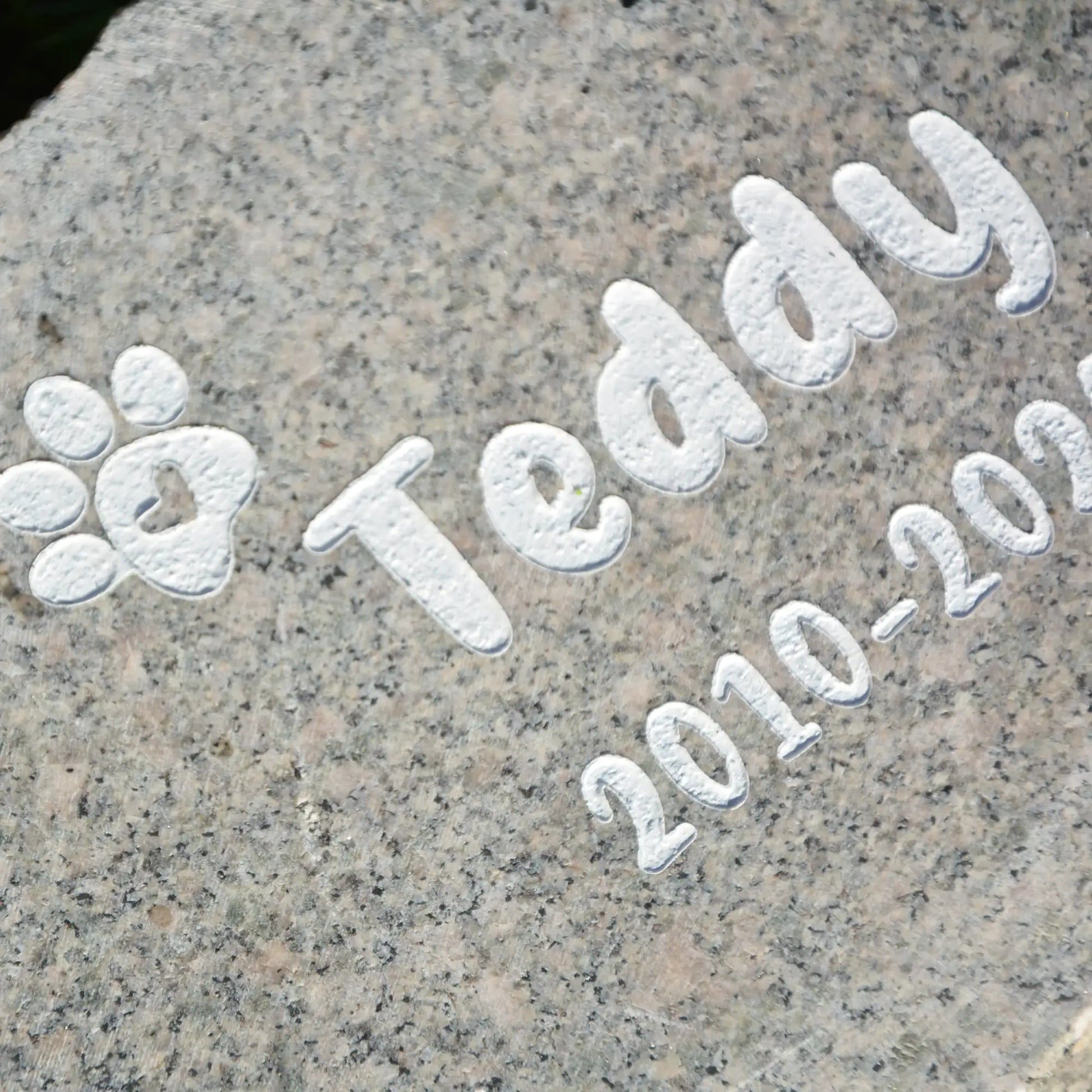 Tiergrabstein Granit mit Pfote und Name. Lebensdaten als weiße Gravur