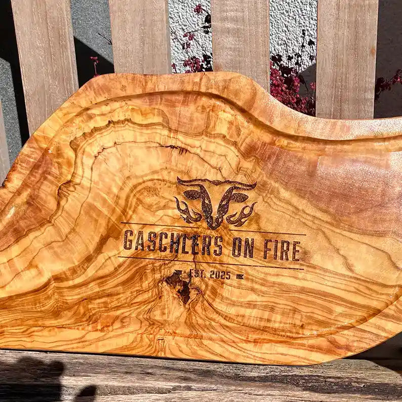 Motiv "On Fire" mit stilisiertem Rinderkopf mit Flammen und  Personaliserungsoption mit Name in Großbuchstaben und Datum - Mediterranes Schneidebrett aus Olivenholz mit Saftrille mit und ohne Grifflasche oder Handgriff - Personalisiertes Männergeschenk von Jeske Design