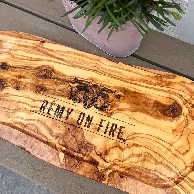 Motiv "On Fire" mit stilisiertem Rinderkopf mit Flammen und  Personaliserungsoption mit Name in Großbuchstaben und Datum - Mediterranes Schneidebrett aus Olivenholz mit Saftrille mit und ohne Grifflasche oder Handgriff - Personalisiertes Männergeschenk von Jeske Design